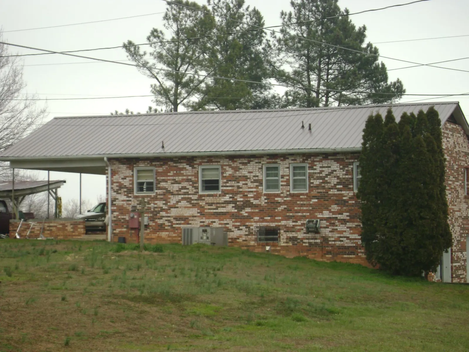 Gray metal roof on a brick split level home with a carport in Farmington